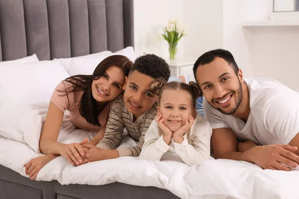 幸せな国際家族が家でベッドに横たわっ — ストック写真