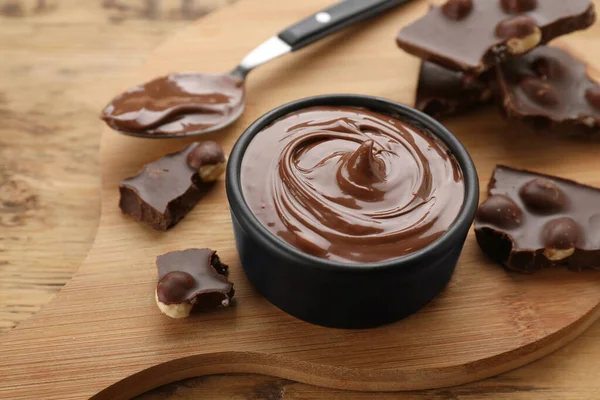 Çikolata parçaları ve bir kase tatlı ezme ahşap masada, yakın plan.