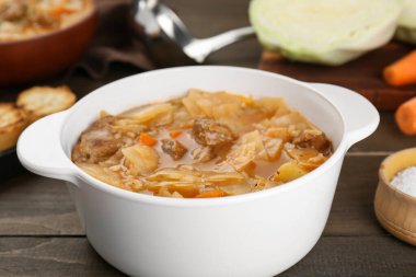 Tasty cabbage soup with meat and carrot on wooden table, closeup