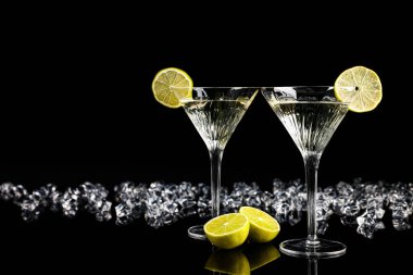 İki bardak Martini kokteyli ve siyah arkaplanda buz küpleri, metin için yer