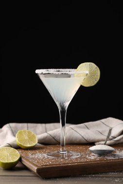 Martini bardağı ferahlatıcı limon ve şeker ile ahşap masa üzerinde siyah arka plan karşı