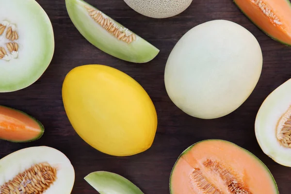 stock image Different types of tasty ripe melons on wooden table, flat lay