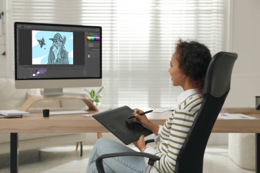 Grafik tablet ve bilgisayar kullanan Afro-Amerikan animasyoncu. Görüntü ekranda