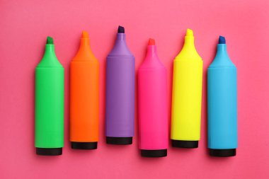 Bright color markers on pink background, flat lay