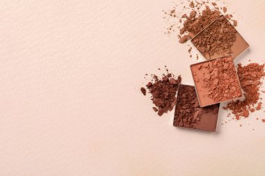 Different crushed eye shadows on beige background, flat lay. Space for text