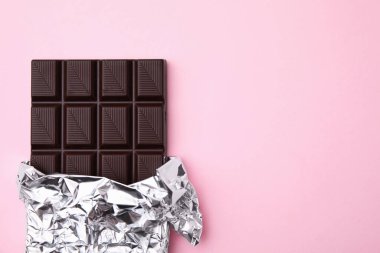 Tasty chocolate bar on pink background, top view. Space for text