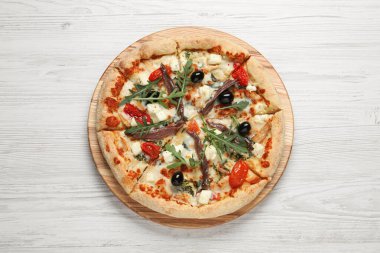 Ançüezli lezzetli pizza, roka ve beyaz masada zeytin.