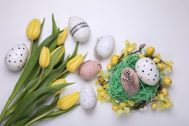 Flat lay composition with beautiful flowers and eggs on white background. Easter celebration