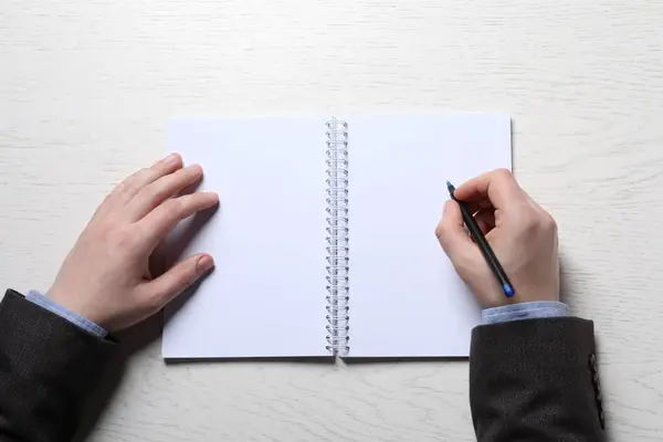 Man Writing Notebook Pen White Wooden Table Top View — Stock fotografie