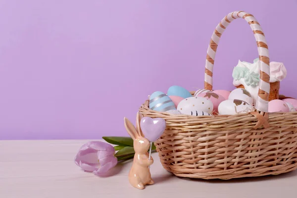 复活节篮子 上面有彩绘的蛋 花和兔子 放在白色的木制桌子上 案文的篇幅 — 图库照片