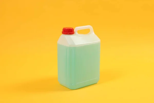 Plastikkanister Mit Grüner Flüssigkeit Auf Orangefarbenem Hintergrund — Stockfoto