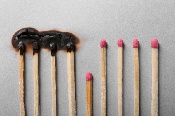 Burnt and whole matches on light grey background, flat lay. Stop destruction by breaking chain reaction concept