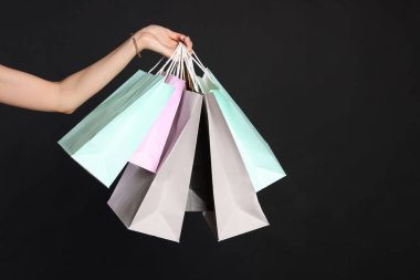 Siyah arka planda alışveriş torbaları tutan kadın, yakın plan. Büyük indirim.