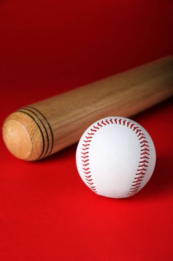 Wooden baseball bat and ball on red background. Sports equipment