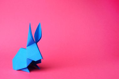 Açık mavi kağıttan tavşancık pembe arka planda, mesaj için boşluk. Origami sanatı