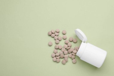 Açık yeşil arka planda bira mayası haplarıyla dolu tıbbi bir şişe. Metin için boşluk