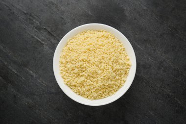 Bowl of tasty couscous on grey table, top view