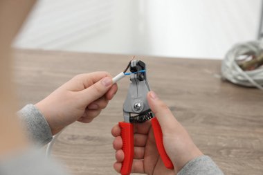 Profesyonel elektrikçi ahşap masada kablo sökme, yakın çekim görüntüsü