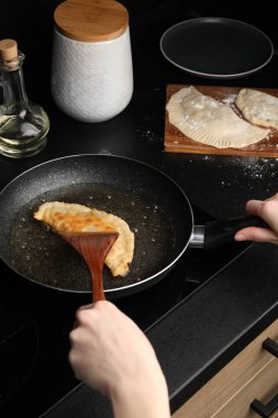 Woman cooking chebureki in frying pan, closeup