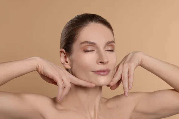 Woman Massaging Her Face Beige Background — Stok Foto