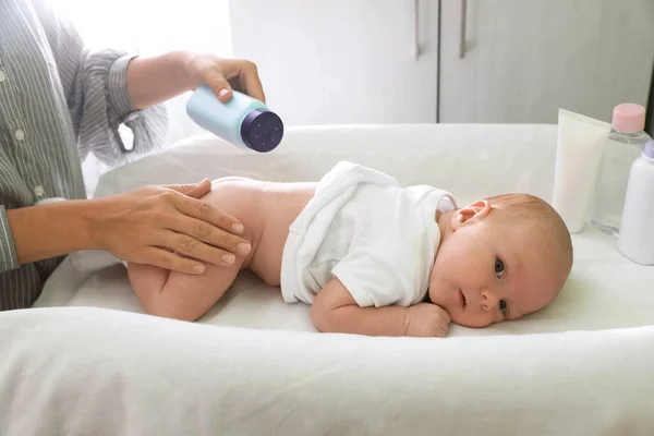 stock image Mother applying dusting powder at baby's buttocks on changing table indoors, closeup