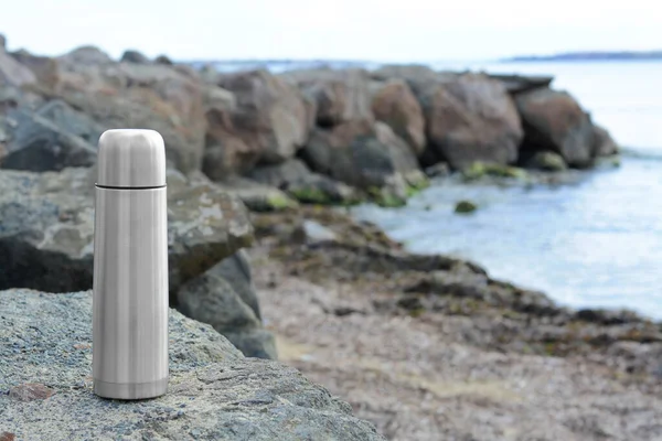 金属热水瓶 在靠近大海的石头上热饮 文字空间 — 图库照片