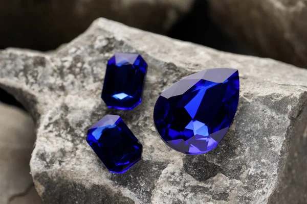 Three beautiful blue gemstones for jewelry on stone surface, closeup