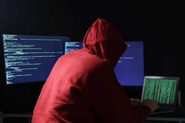 Hacker karanlık odada bilgisayarlarla çalışıyor. Siber saldırı