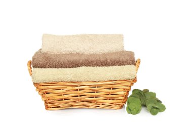 Wicker basket with folded soft terry towels and eucalyptus branch on white background