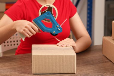 Postane çalışanı kapalı gişede paket topluyor, yakın plan.