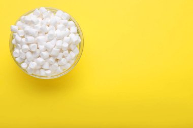 Sarı arka planda leziz marşmelovlu cam kase, üst manzara. Metin için boşluk