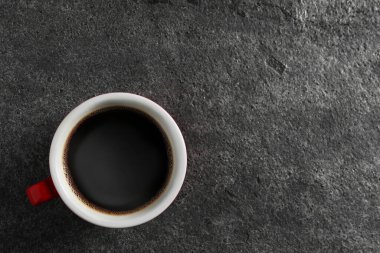 Cup with aromatic coffee on grey textured table, top view. Space for text