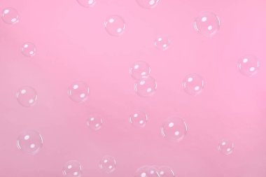 Many beautiful soap bubbles on pink background
