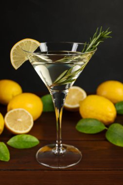 Limon dilimli martini kokteyli, biberiye ve ahşap masada taze meyve.