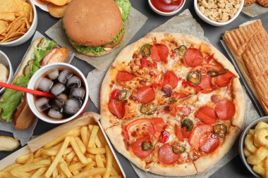 Pizza, hamburger ve diğer fast food siyah masada, düz yerde