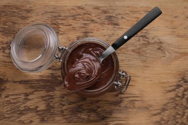 Cam kavanoz ve kaşık dolusu çikolata, ahşap masa, üst manzara.