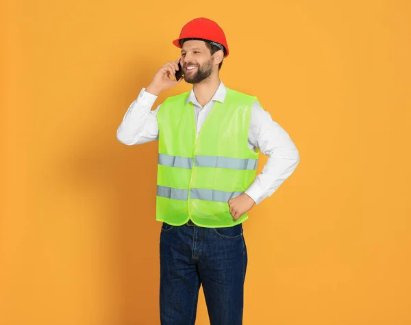 Mann Reflektierender Uniform Spricht Auf Smartphone Vor Orangefarbenem Hintergrund — Stockfoto