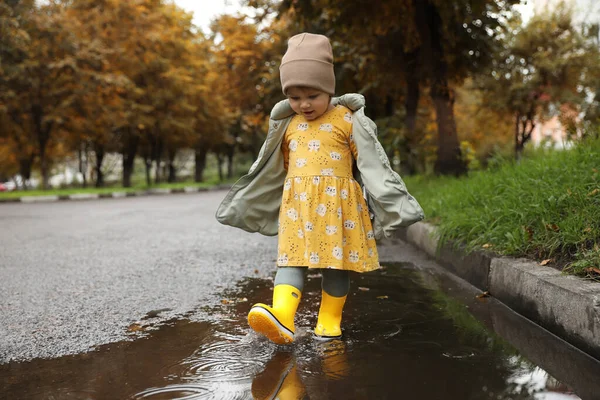 Cute Little Girl Splashing Water Her Boots Puddle Outdoors — ストック写真