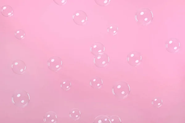 Many beautiful soap bubbles on pink background