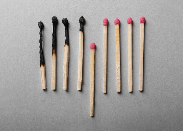 Burnt and whole matches on light grey background, flat lay. Stop destruction by breaking chain reaction concept