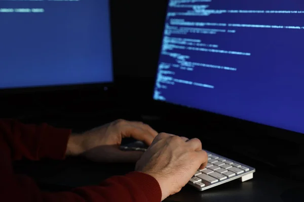 Hacker working with computers in dark room, closeup. Cyber attack