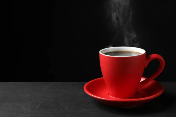 黒を背景に灰色のテーブルの上に熱い蒸しコーヒーと赤カップ テキストのためのスペース — ストック写真