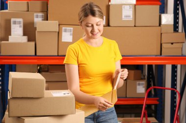 Kapalı mekanda kağıt torba taşıyan bir postane çalışanı.