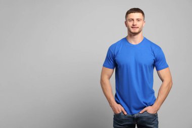Açık gri arka planda mavi tişört giyen bir adam. Tasarım için model