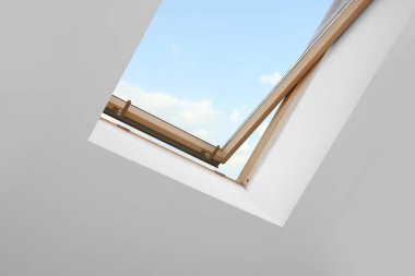 Skylight roof window and lamps on slanted ceiling in attic room, low angle view
