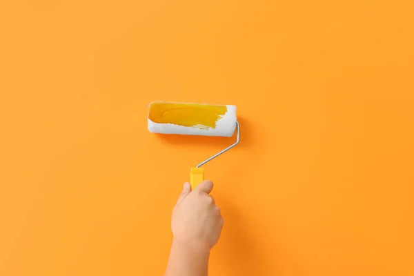 Worker using roller to paint wall with orange dye, closeup