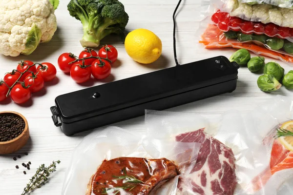 Vacuum packing sealer and different food products on white wooden table
