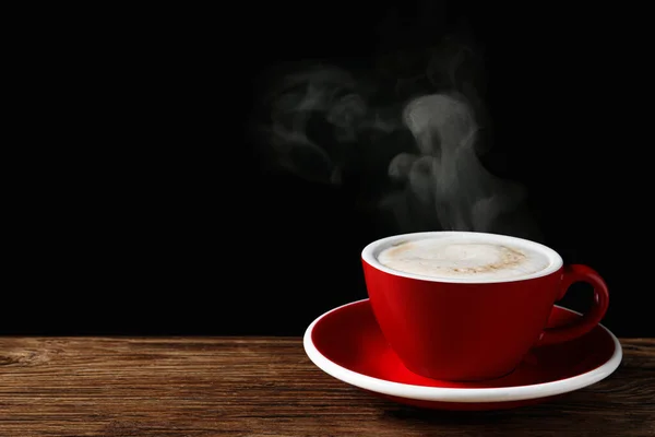 黒を背景に木製のテーブルの上に熱い蒸しコーヒーと赤カップ テキストのためのスペース — ストック写真