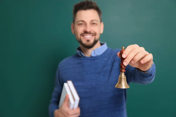 Teacher with school bell near chalkboard. Focus on hand