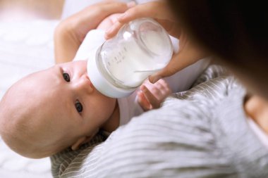 Mother feeding her little baby from bottle, closeup
